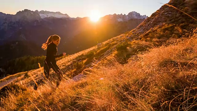 一个年轻女子在日落时分跑上了山视频素材