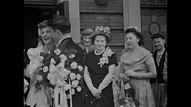 20世纪40年代，一对新婚夫妇在教堂外摆姿势拍照，而家人和朋友则在扔米饭视频素材