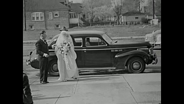 20世纪40年代，新娘和父亲一起开着老古董车到达教堂/婚礼宾客在教堂外等候/伴娘到达教堂视频素材