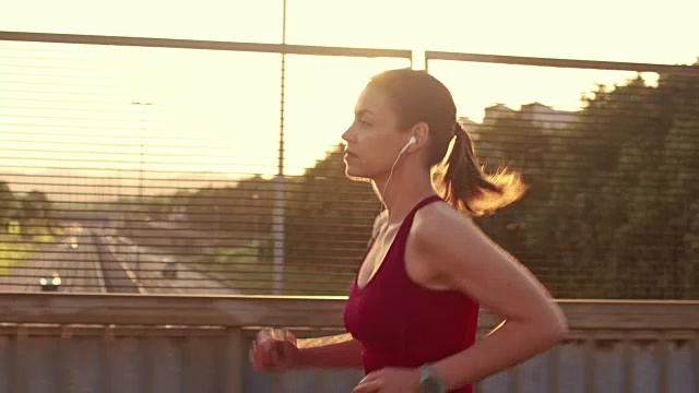 SLO MO女人慢跑过一个高速公路立交桥在日落视频素材
