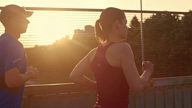 SLO MO TS夫妇在日落时分在城市慢跑视频素材