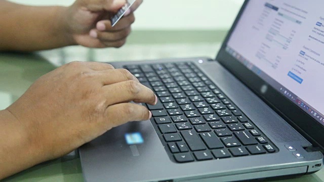 男性手握信用卡在电脑键盘上输入数字。视频素材