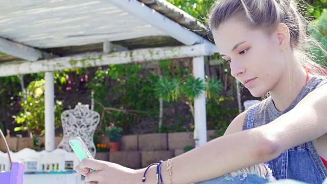 年轻女子在花园里用智能手机视频素材