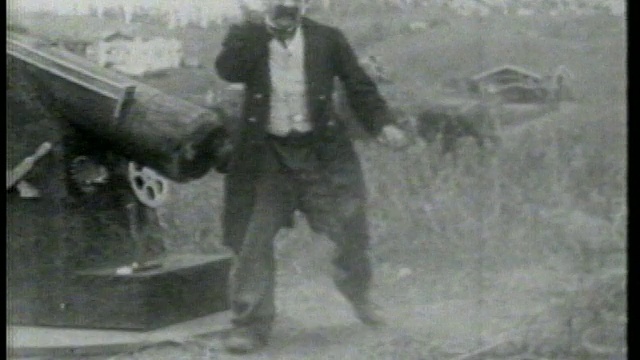 1915年，一名男子(切斯特·康克林)站在大炮附近的草地上，踉跄着视频素材