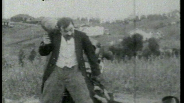 1915年，一名男子将炮弹装进大炮，第二名男子昏迷不醒地躺在大炮旁边视频素材