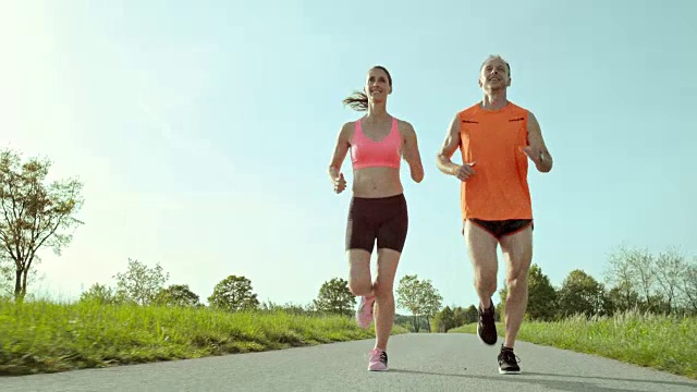 SLO MO TS女人和男人在绿色的周围奔跑视频下载