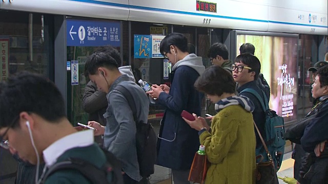 人们用手机等地铁视频下载