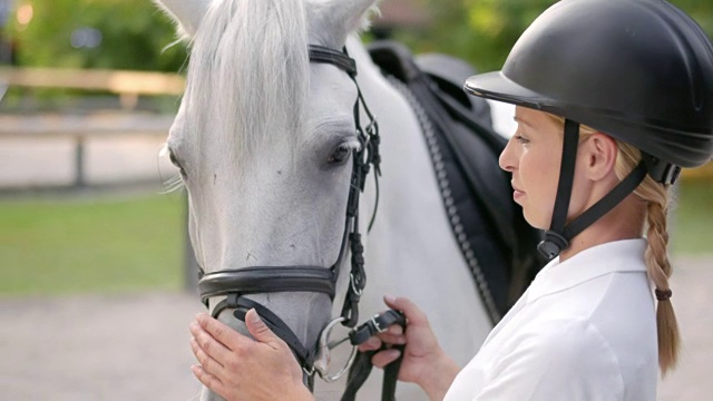 女骑手抚摸着她的白马的鼻子视频素材