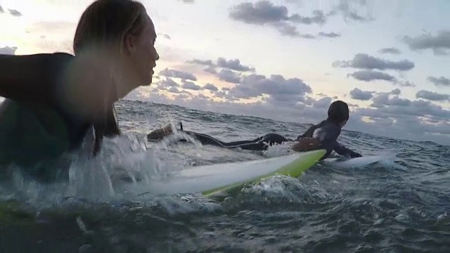 日落时分，法国南部，两名女性冲浪者在海上划着冲浪板视频下载