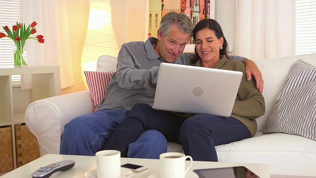 一对老年夫妇微笑着使用笔记本电脑视频素材