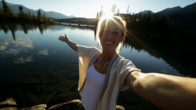 日落时分，一名年轻女子在湖边自拍视频素材