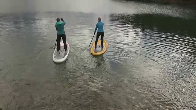 两名妇女用桨划过山湖视频下载