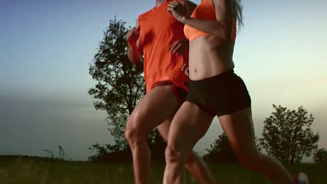 SLO MO TS夫妇在日落时在大自然中跑步视频素材