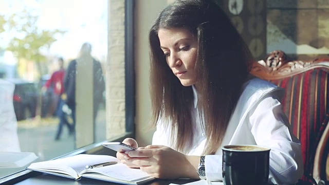 年轻的商业女性在咖啡店浏览她的智能手机。视频素材