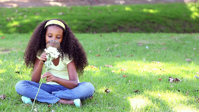 小女孩坐在草地上看花视频素材