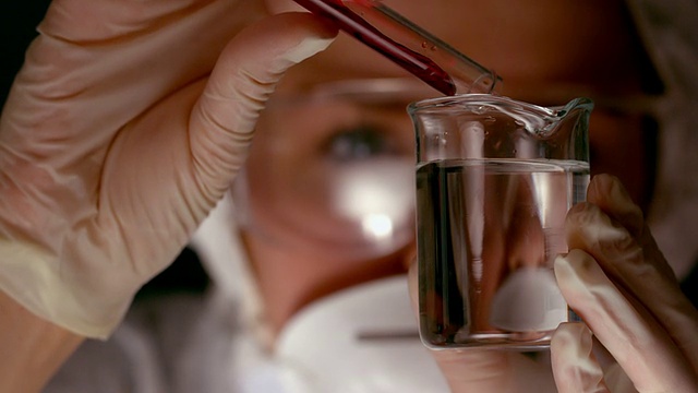 科学家将红色化学品倒入烧杯视频素材
