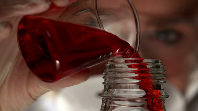 科学家将红色液体倒入瓶中视频素材