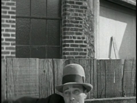 1928年B/W近距离微笑的男子在帽子被击中的头与木板/短视频素材