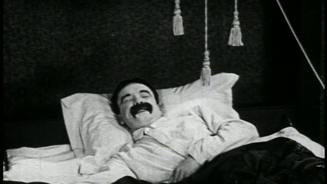 1923年一个男人(Snub Pollard)在床上醒来+拉着挂在他头上的绳子/新闻短片视频素材