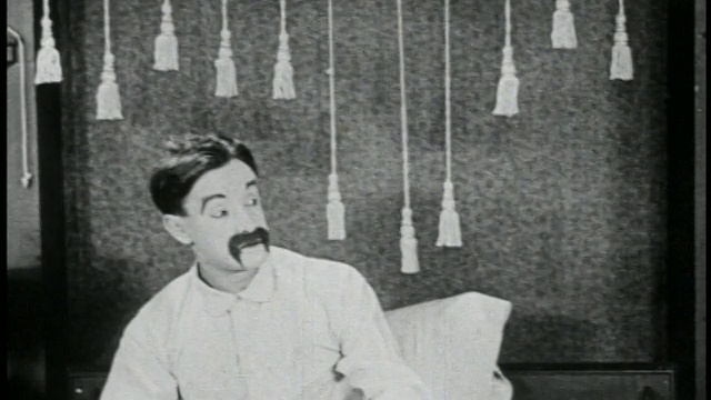 1923年B/W男子(Snub Pollard)在床上伸展/短视频素材