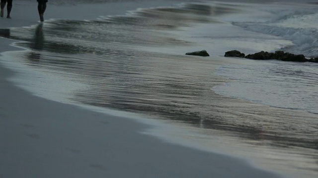 夫妇慢跑通过轻拍的波浪在黄昏，长湾，安提瓜，加勒比视频下载