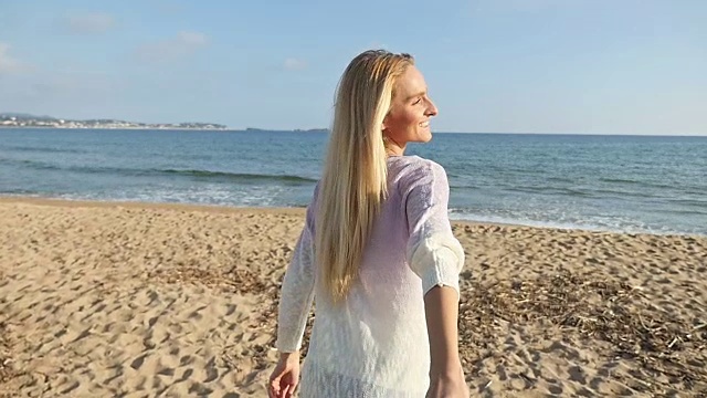 一个快乐的女人在海滩上奔跑的背影视频素材