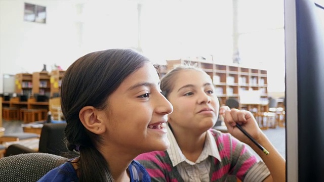 两名西班牙裔女中学生在STEM学校图书馆或计算机实验室研究计算机信息视频素材