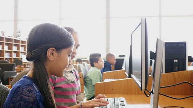 两名青春期前的中学女学生在STEM学校图书馆或计算机实验室从事项目工作视频下载