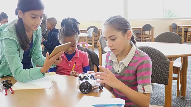 两名西班牙裔女小学生与年轻的非洲裔美国女学生在STEM学校研究机器人视频素材