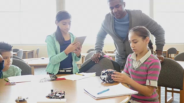 非裔美国男性成年教师指导小学和中学学生与机器人工作视频下载