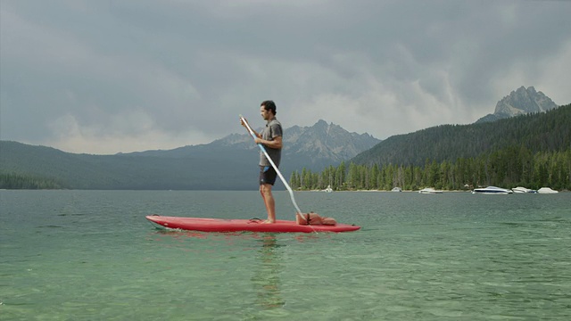 宽阔的镜头年轻男子在湖/红鱼湖，爱达荷州，美国视频下载