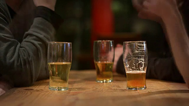 靠近啤酒杯在和在传统的英国酒吧朋友社交和享受一个生动的谈话视频素材