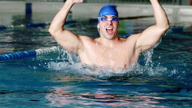 年轻的男子游泳运动员在泳池里欢呼视频素材