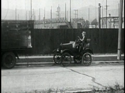 1928年，一名男子(拉里·西蒙)开着车停在街上/被卡车拦住+他掉了出来/特写视频素材