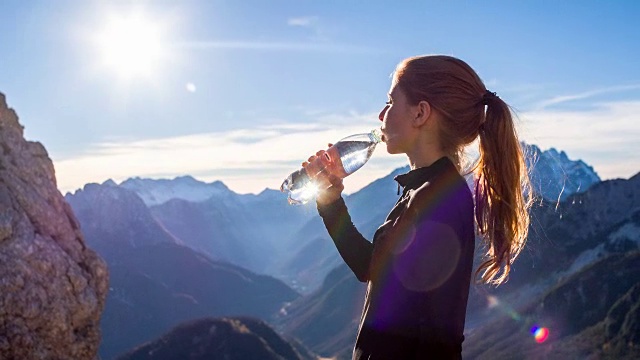 在山顶喝水的年轻女子视频素材