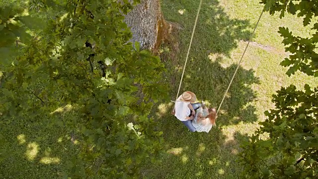 CS俯视着一对在树林中荡秋千的情侣视频素材