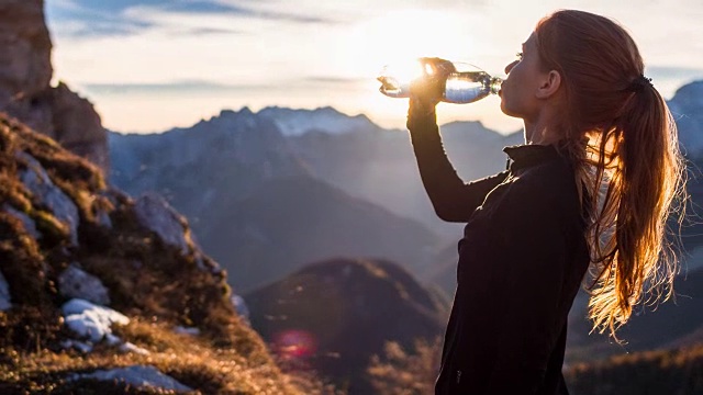 在山顶喝水的年轻女子视频素材