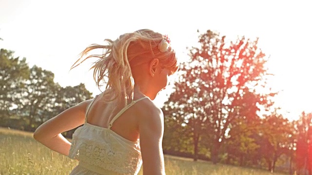 SLO MO TS小女孩在阳光明媚的草地上奔跑视频素材
