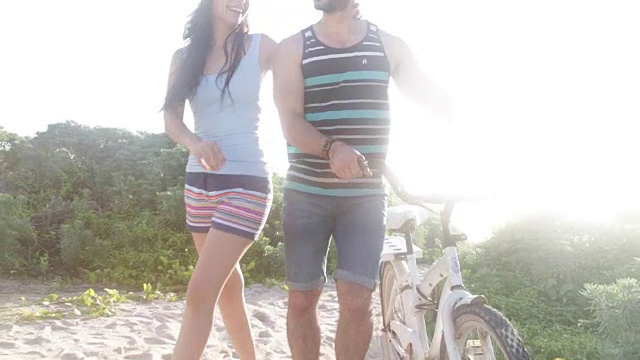 一对推着自行车在沙地上散步的夫妇。视频下载