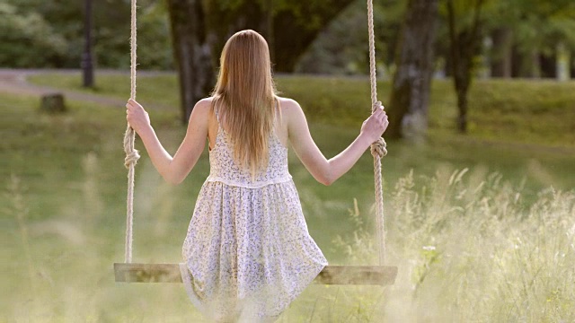 SLO MO DS女人穿着一件夏季连衣裙在大自然中摇摆视频素材