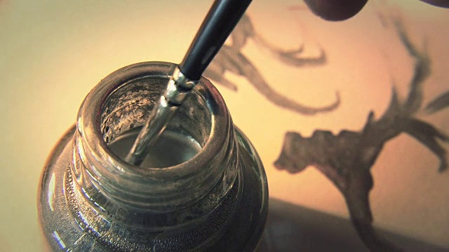 艺术家将画笔浸入颜料桶中，特写视频素材