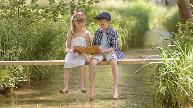 一个男孩和一个女孩坐在人行桥上看书视频下载