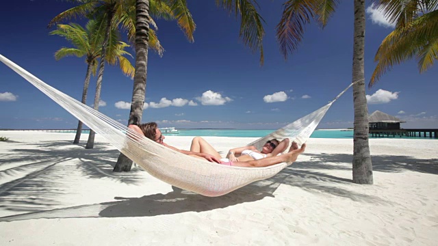 一对夫妇在热带海滩的吊床上放松视频下载