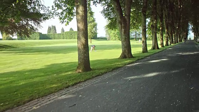 SLO MO女人慢跑穿过公园在一个阳光明媚的日子视频素材