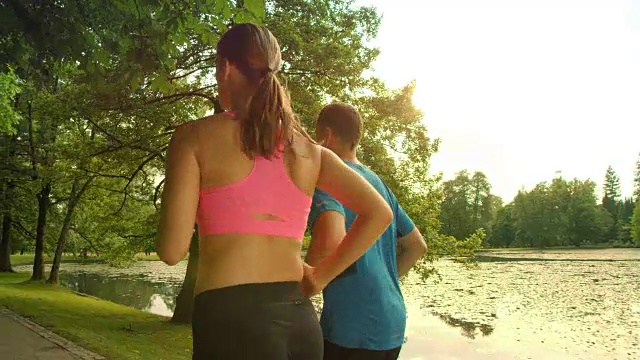 一对情侣在阳光下沿着湖边慢跑视频素材