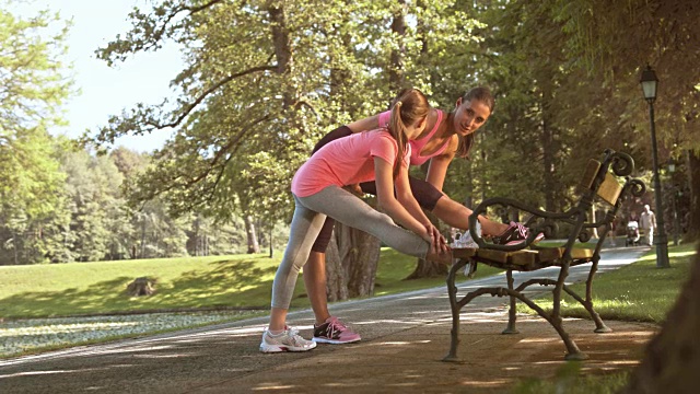 母亲和女儿在公园的长椅上伸懒腰视频素材