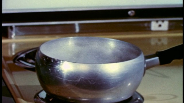 1958年，用沸水将金属平底锅从炉顶电炉中取出视频素材