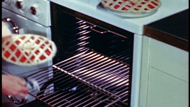 1946年，女人的手把两个馅饼放到烤架上+推烤架进烤架+关上烤炉门视频素材