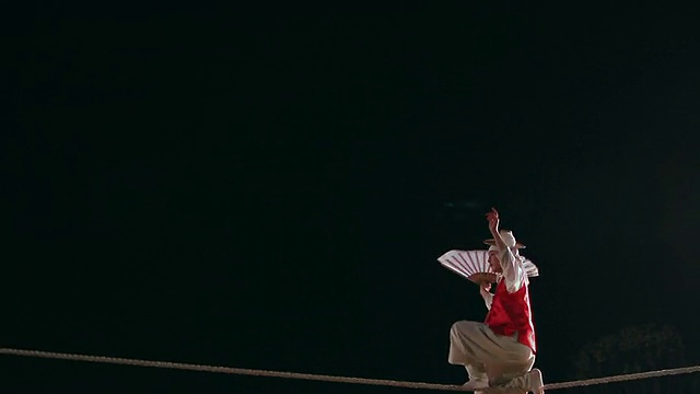 MS摄于韩国京畿道，一名走钢丝者在夜间高空钢丝上表演杂技视频下载