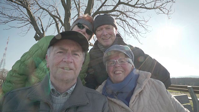四个快乐的老年人在阳光明媚的冬日微笑视频下载